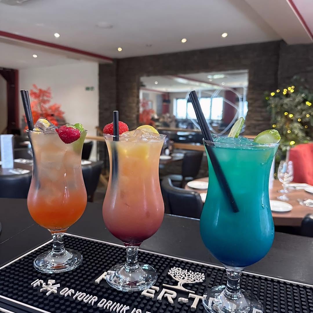 Three colourful mocktails garnished with fruit on the bar at Rosa Twelve