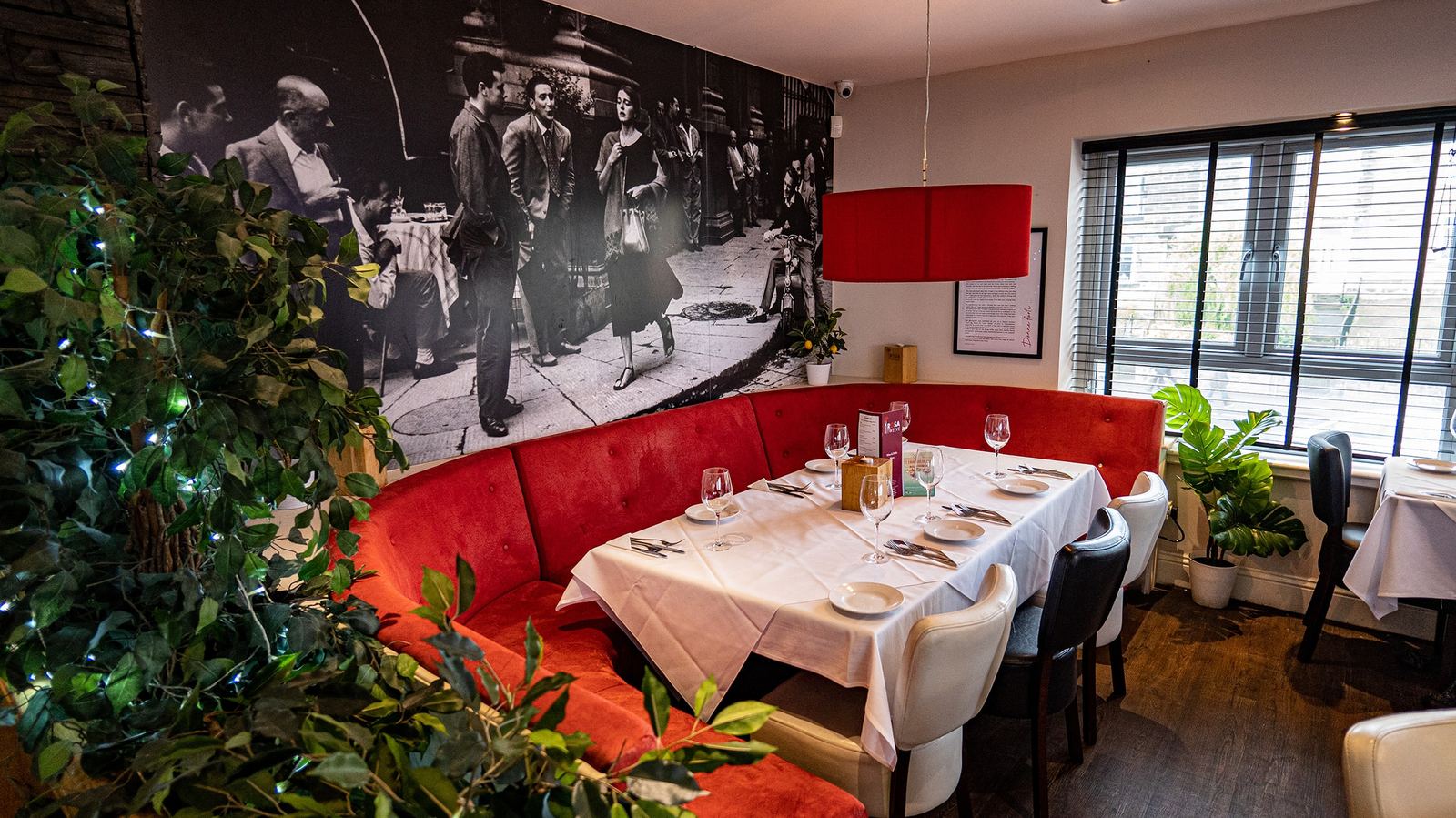 A red banquette beneath a black-and-white street-scene mural at Rosa Twelve